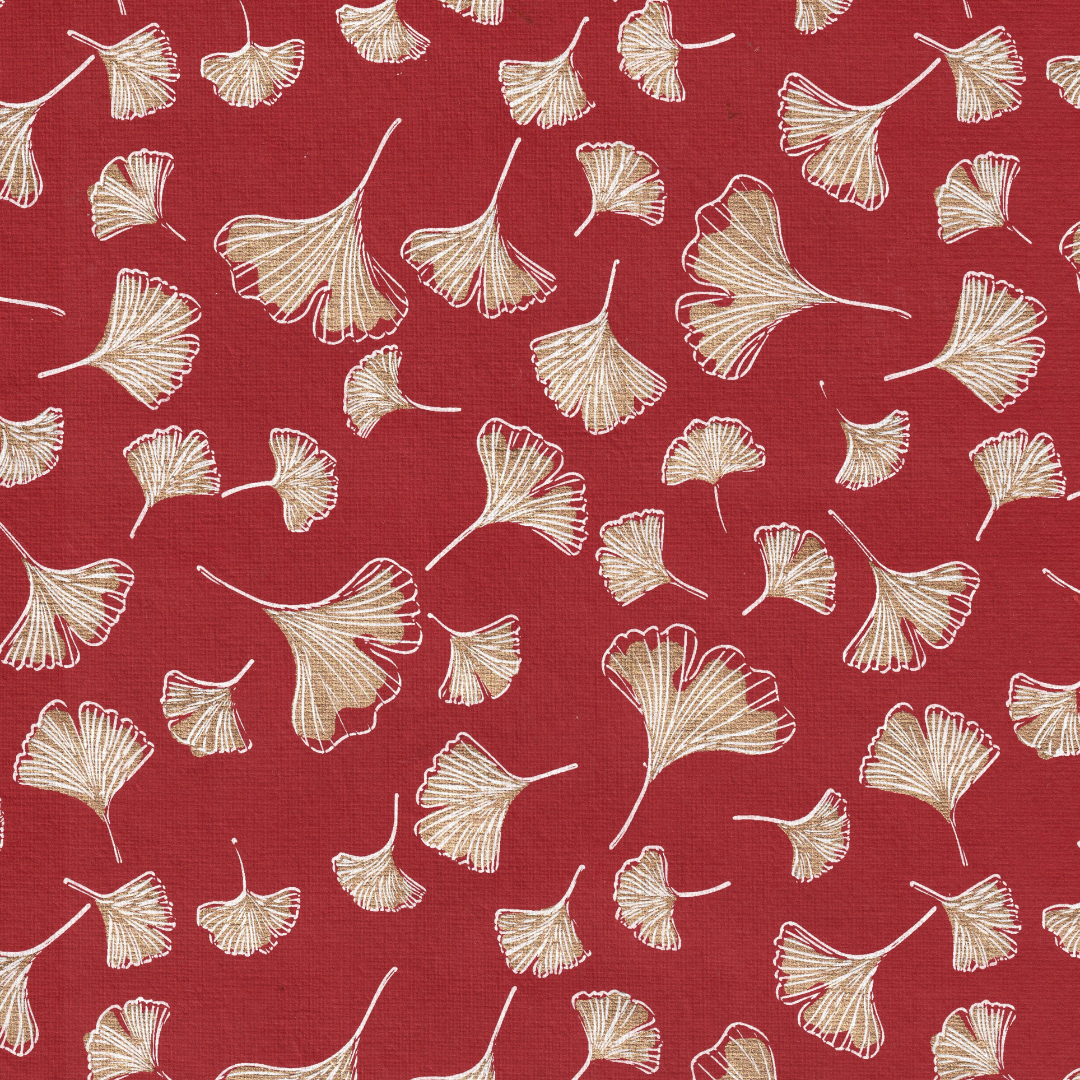 Pattern of pale gold ginkgo leaves spread across a red textured background. Papier rouge avec un motif de gingko rouge et or
