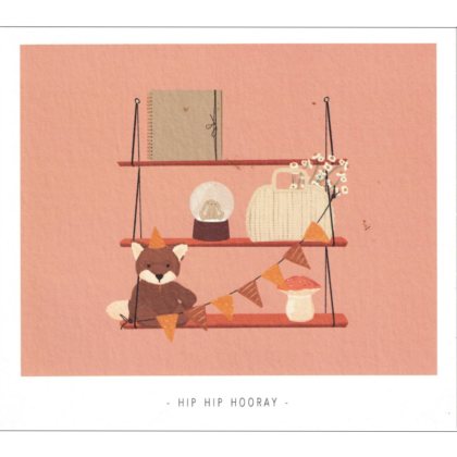 Three-tier wall shelf on a pink background holding a notebook, glass dome, woven basket, bunting, a mushroom ornament, and a small fox with a party hat.