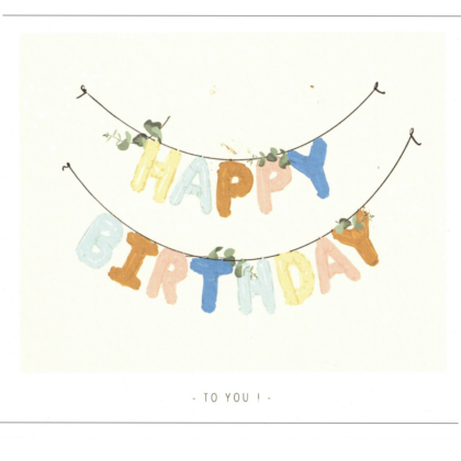 Colorful 'HAPPY BIRTHDAY' banner hanging on a string with green leaves on a light background, 'TO YOU' below.